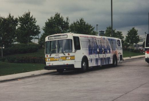 A white Pace Orion V bus with fleet number 8820 is parked on a street, displaying a side advertisement and an overcast sky in the background.