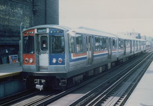 A silver, blue, and red rapid transit train with an orange front panel, numbered 610, at an elevated station platform. The destination sign reads 'Jackson Pk Howard B'.