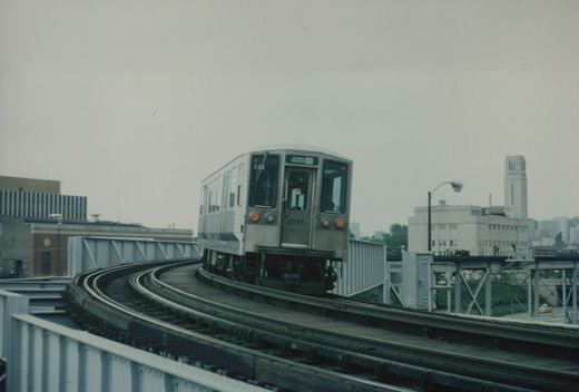 A silver CTA 2200-series 'L' car numbered 2256 rounds a curve on an elevated track on an overcast day.