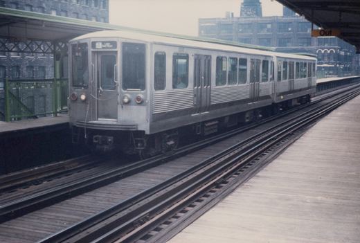 A silver Chicago Transit Authority 2200-series rapid transit car, numbered 2230, is stopped at an elevated station platform with a green roof and a 'Lake Dan Ryan' destination sign.