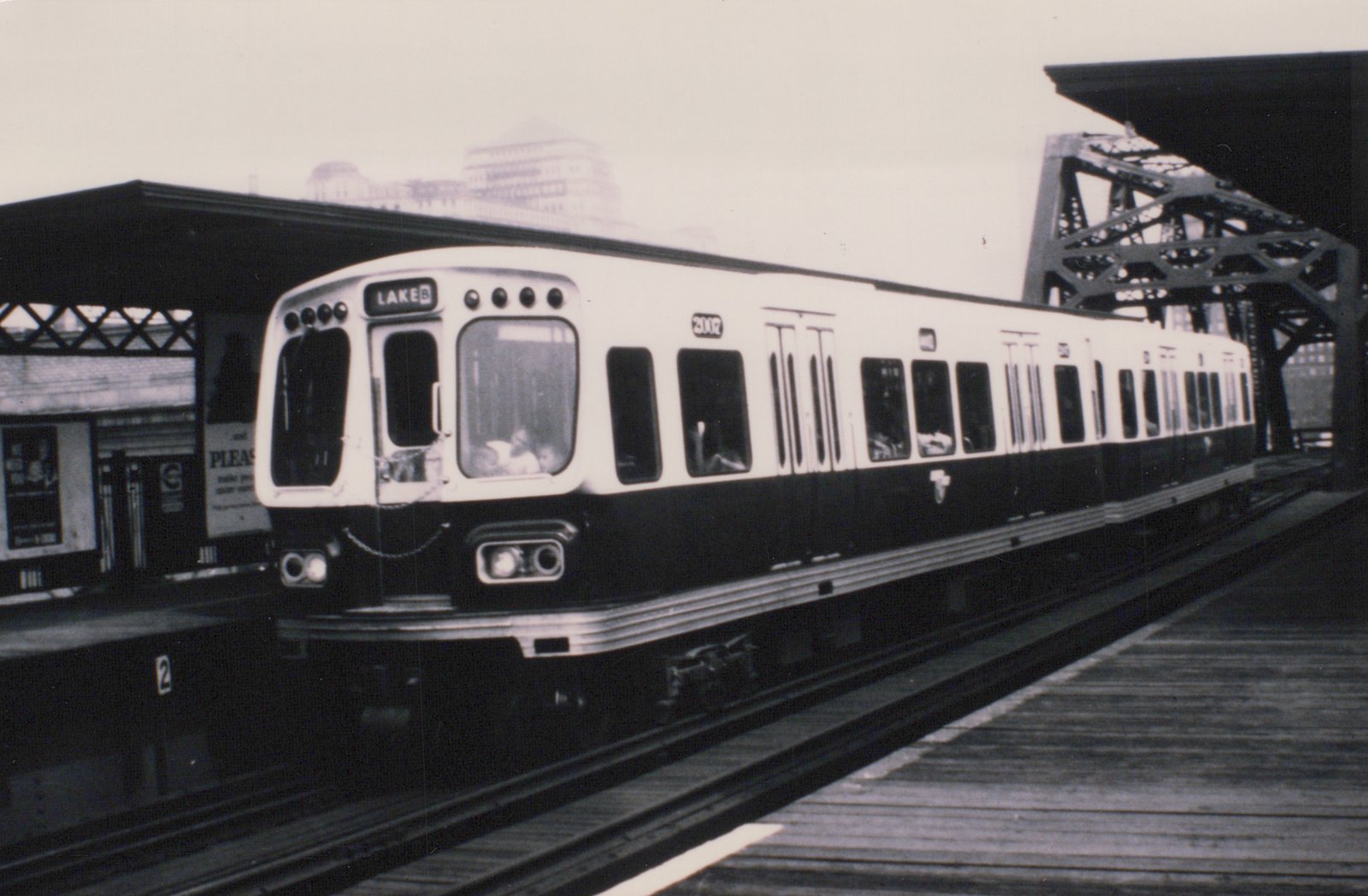 A black and white photo of a CTA 2000-series rapid transit car, number 2002, stopped at an elevated station platform with its destination sign reading 'LAKE B'.