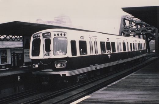 A black and white photo of a CTA 2000-series rapid transit car, number 2002, stopped at an elevated station platform with its destination sign reading 'LAKE B'.