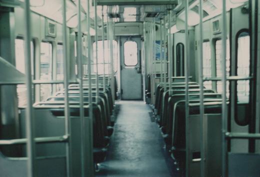 A view down the aisle of an empty Chicago Transit Authority rapid transit car, number 2001, showing rows of seats, handrails, and the cab door at the far end.