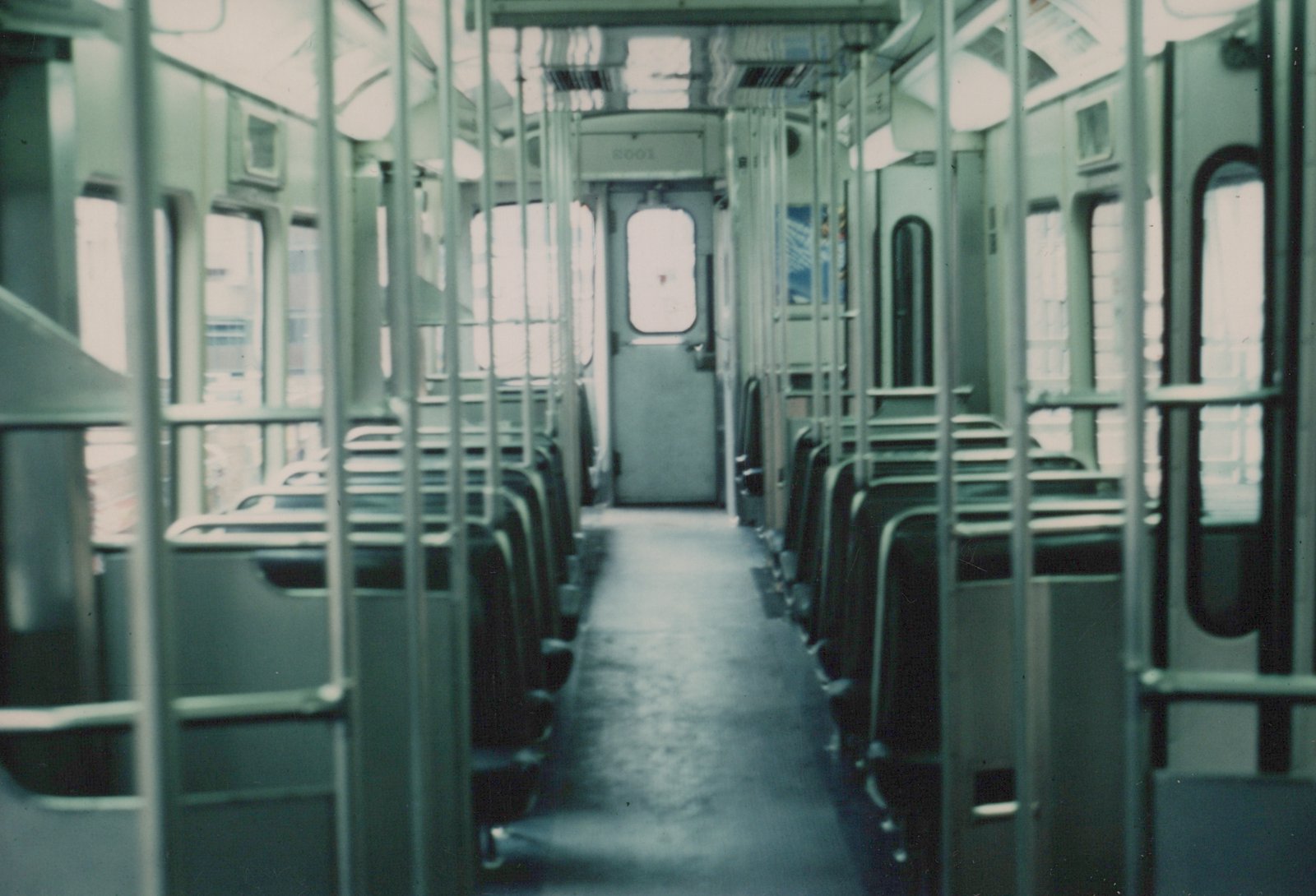 A view down the aisle of an empty Chicago Transit Authority rapid transit car, number 2001, showing rows of seats, handrails, and the cab door at the far end.