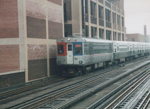 A gray and red CTA rapid transit train on elevated tracks next to a brick building, with the number 28 and destination 'Evanston Express' visible.