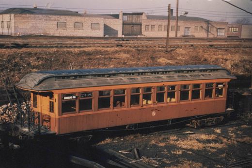 An orange interurban car numbered 233S is parked on railroad tracks in a yard, with destination signs for 'DOUGLAS PK.' and 'LOOP.' visible on its ends.