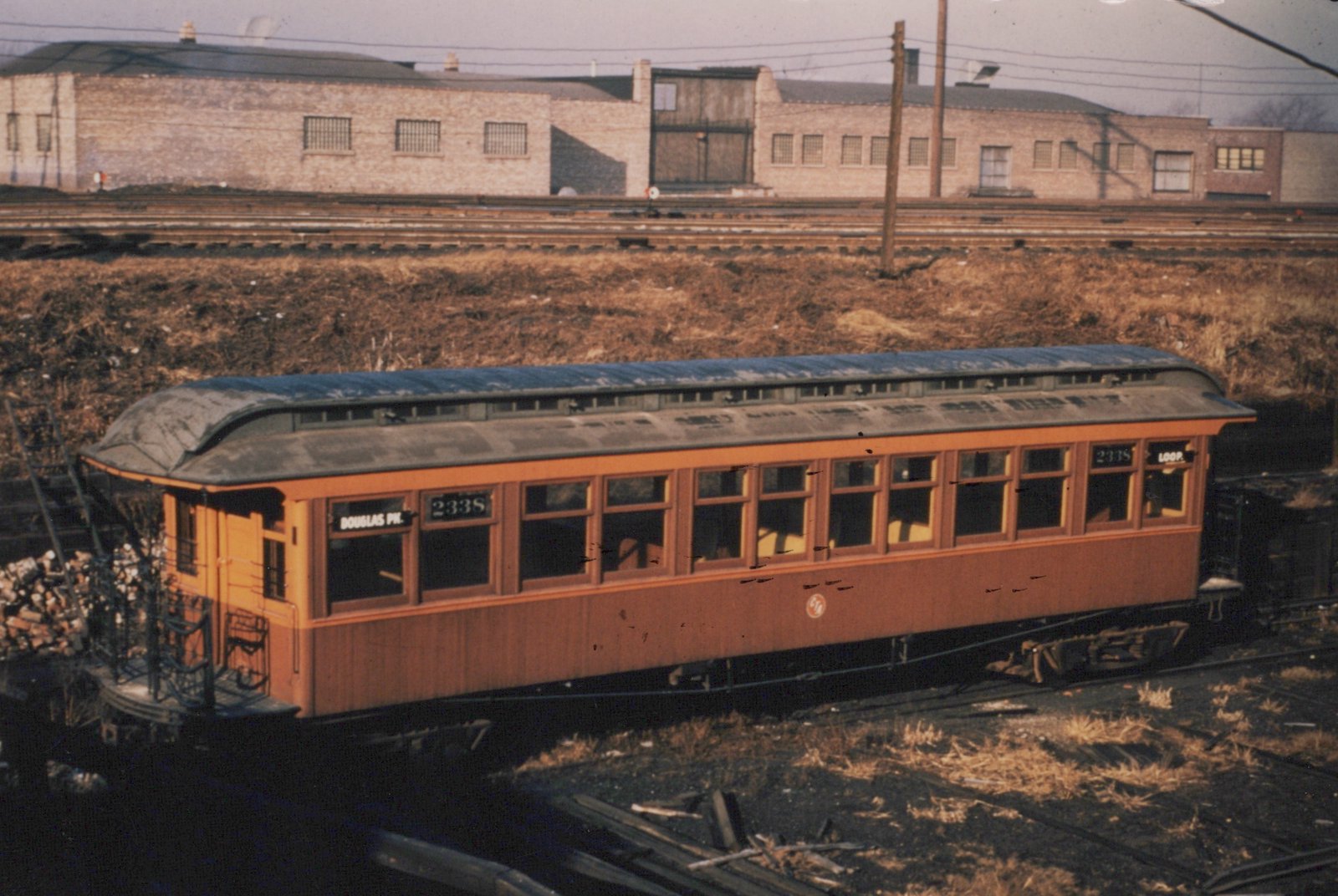 An orange interurban car numbered 233S is parked on railroad tracks in a yard, with destination signs for 'DOUGLAS PK.' and 'LOOP.' visible on its ends.