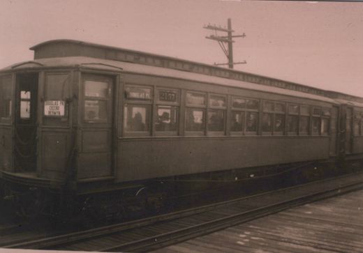 A black-and-white photo of a vintage Chicago Aurora and Elgin interurban car, number 2157, on an elevated track with passengers visible inside; signs indicate routes to Douglas Park, Cicero, and Berwyn.