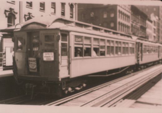 A vintage black-and-white photo of a Chicago 'L' car, number 1149, with a rear destination sign reading 'EXPRESS HOWARD ST', on elevated tracks with city buildings in the background.