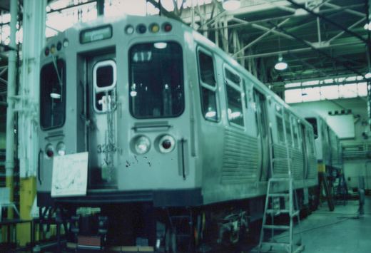 A stainless steel Chicago Transit Authority rapid transit car, number 3205, is parked inside a maintenance shop with a sign above the windshield reading 'Englewood Loop'.