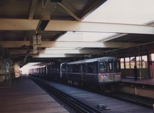 An elevated train station with a blue and silver Chicago Transit Authority rapid transit car, number 2774, stopped at the platform, with 'Evanston Express' displayed on its sign.