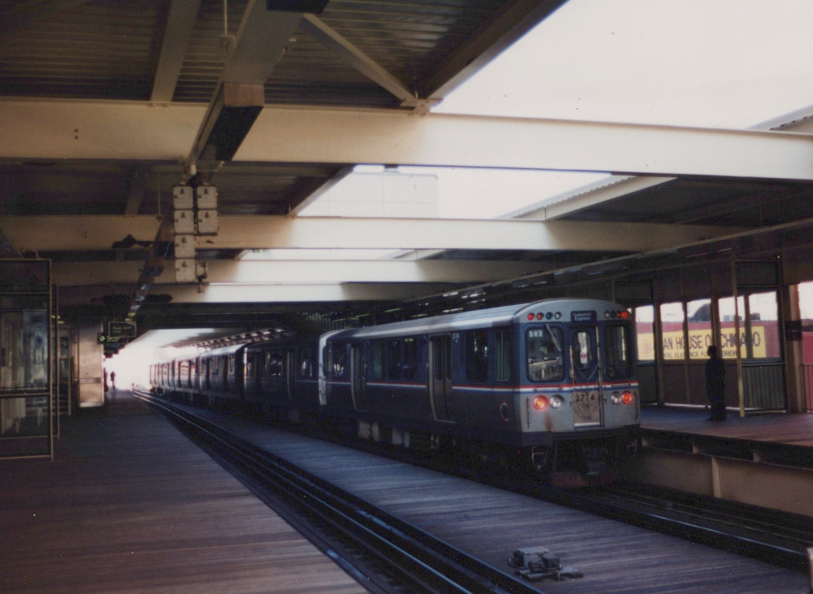 An elevated train station with a blue and silver Chicago Transit Authority rapid transit car, number 2774, stopped at the platform, with 'Evanston Express' displayed on its sign.