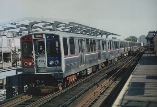 A silver CTA 2600 series train, number 2542, is stopped at an elevated station platform under a modern canopy, with 'Howard' and 'Dan Ryan' shown on the destination sign.