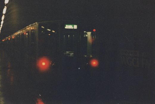 A dark rapid transit train with a green illuminated destination sign reading 'Douglas Milwaukee B' is visible in a subway tunnel at night.