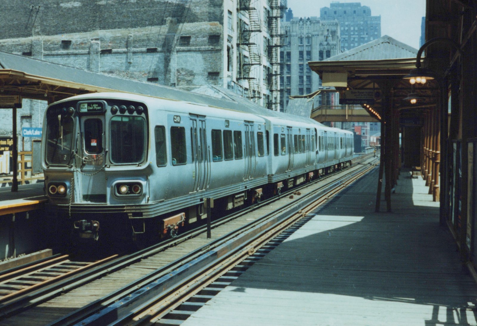 A silver CTA train with the number 249 and destination 'Lake Dan Ryan' is stopped at an elevated station platform with the sign 'Clark/Lake' visible.