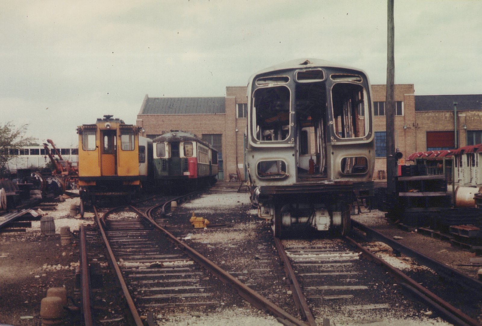 Three different types of electric railcars, one a Chicago Transit Authority rapid transit car and two former Chicago North Shore and Milwaukee interurban cars, are shown in a rail yard, with the front car stripped of its interior and equipment.