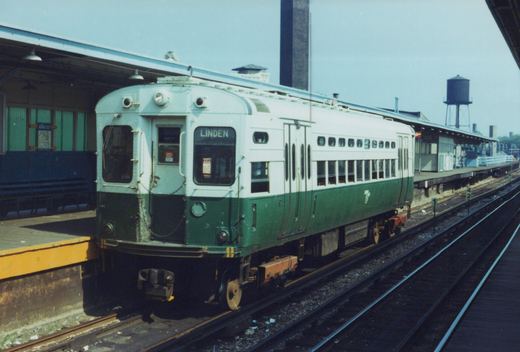 A vintage green and cream Chicago Transit Authority rapid transit car numbered 46 is at a station on an elevated structure, with a Linden destination sign and a water tower visible in the background.