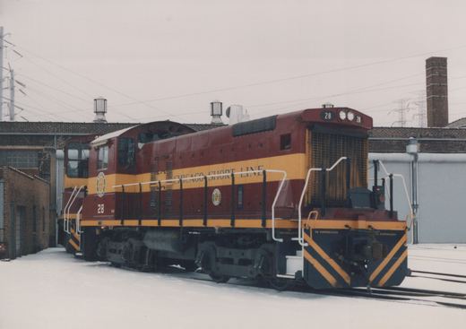 A maroon and yellow diesel locomotive labeled Chicago Short Line with number 28, parked in a snowy industrial yard.