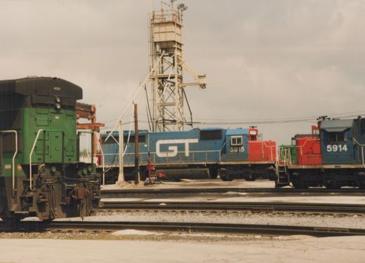 Three diesel locomotives, including GM&O 5915 and 5914, are parked in a railroad yard under an overcast sky.