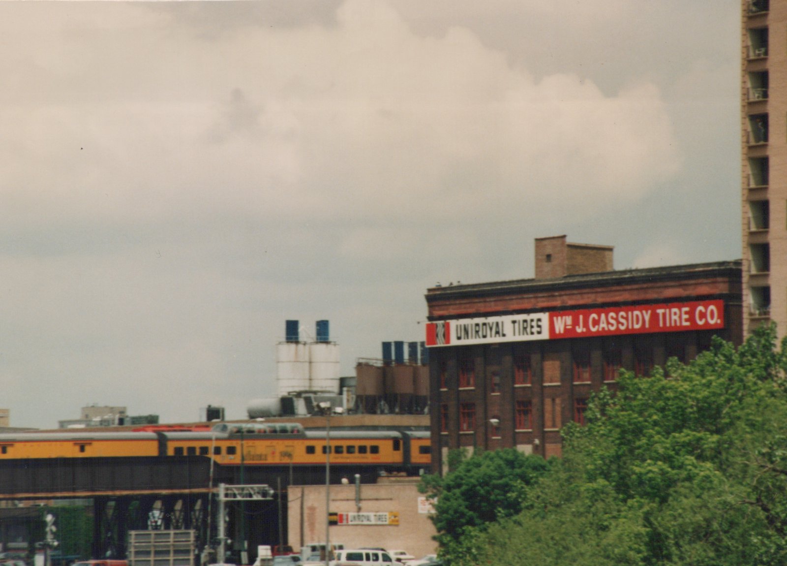 A Metra gallery car on an elevated track in Chicago, with the Wm J. Cassidy Tire Co. sign on a building behind it.