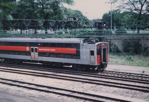 A silver and orange electric train car with the number 1597 and Regional Transportation Authority lettering, viewed from the rear quarter on multiple railroad tracks.