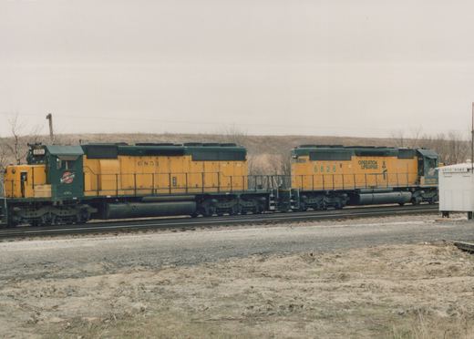 Side view of two yellow and green diesel locomotives coupled on a track with a white signal house labeled 'BRYN MAWR' to the right, in a winter landscape.
