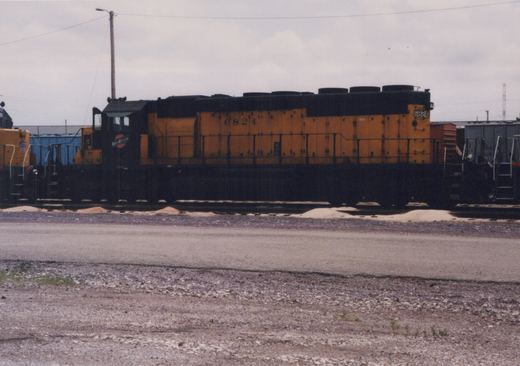 Side view of a yellow and black diesel locomotive numbered 6824 with 'NORTHWESTERN' lettering on the cab, parked on tracks in a gravel yard under an overcast sky.