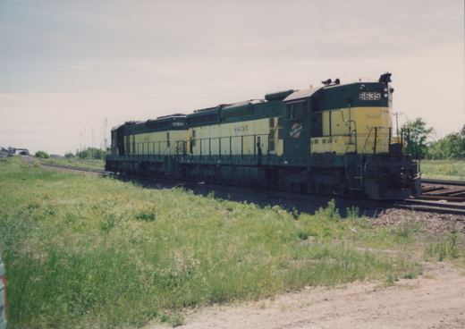 Two diesel locomotives with green and yellow paint, numbers 6635 and 6630, on a railroad track with grass and trees nearby.