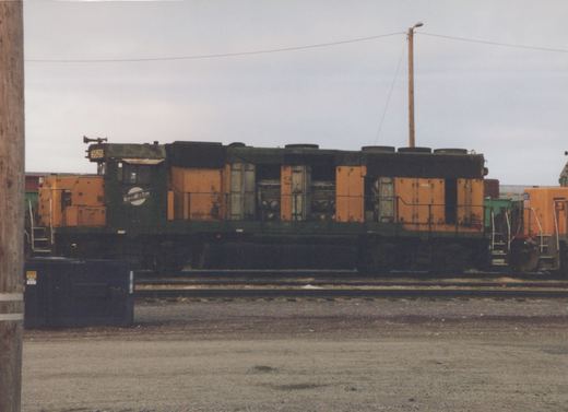 A green and yellow diesel locomotive with the number 5525 and a Northwestern herald sits on tracks in a gravel yard.