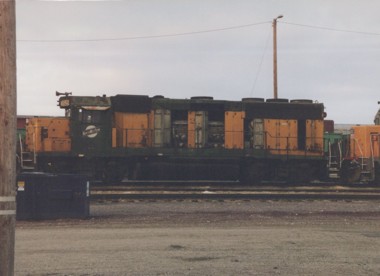 A green and yellow diesel locomotive with the number 5525 and a Northwestern herald sits on tracks in a gravel yard.
