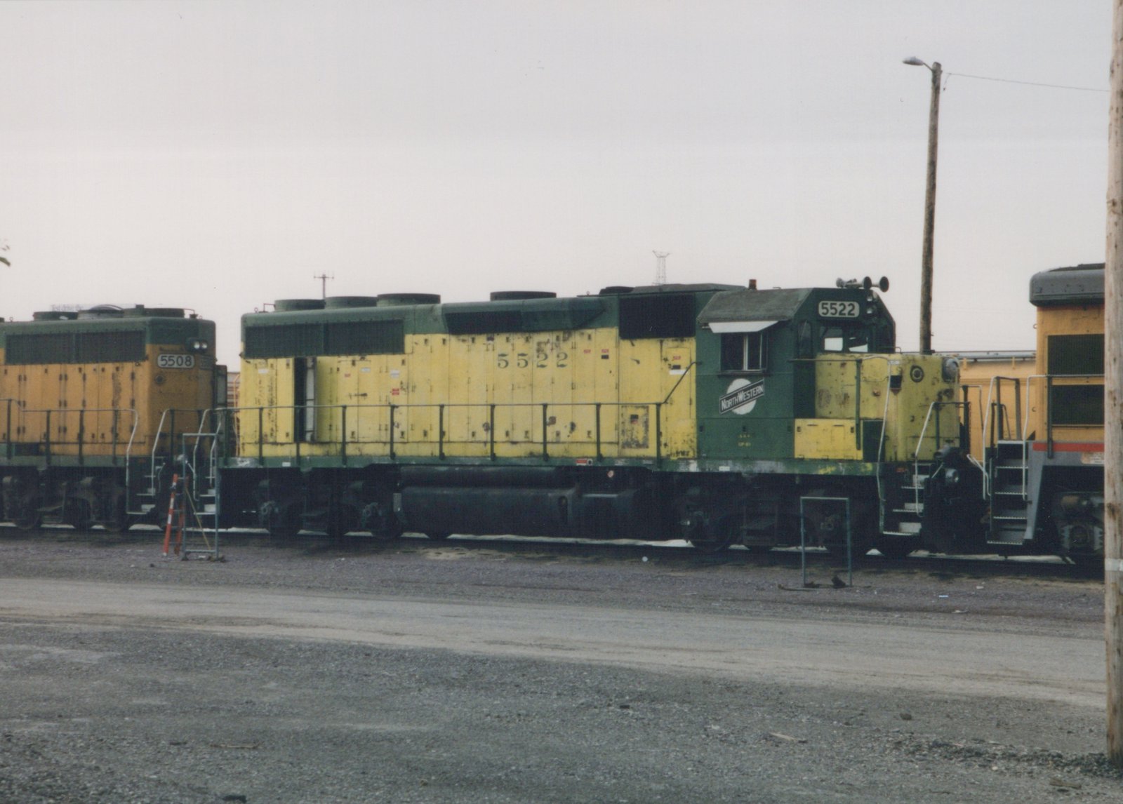 Side view of two Chicago and North Western diesel locomotives, numbers 5522 and 5508, parked in a gravel yard under an overcast sky in May 1999.