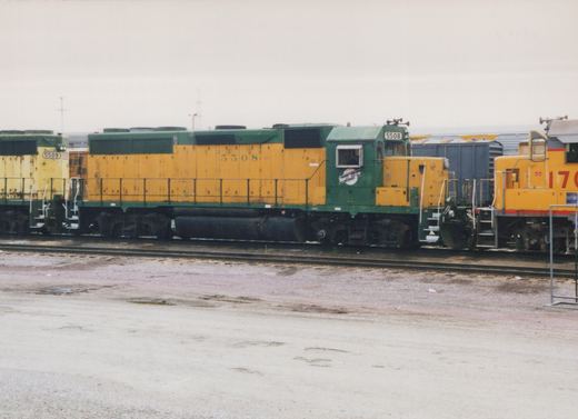 Three Chicago and North Western diesel locomotives, including SD24 number 5508, parked side-by-side in a rail yard under an overcast sky.
