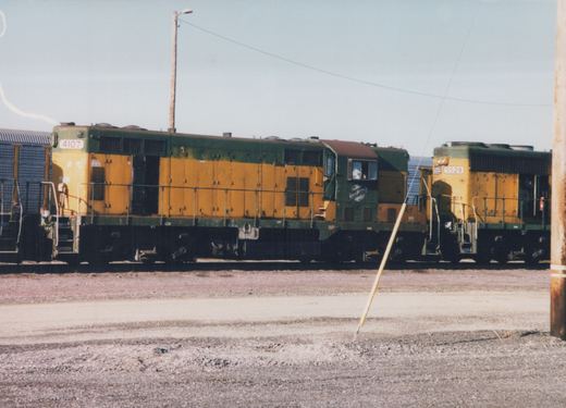 Two diesel locomotives in Chicago and North Western green and yellow livery are parked on parallel tracks in a yard, with number 4107 in front and 5529 behind.