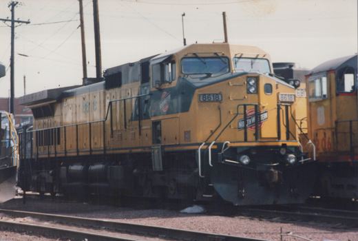 A yellow and dark green diesel locomotive with the number 8618 and 'NORTHWESTERN' lettering on the front, parked on tracks in a yard.