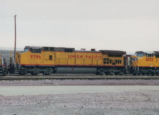 Two yellow Union Pacific diesel locomotives, numbered 9786 and 4032, are parked side by side in a gravel rail yard under a gray sky.