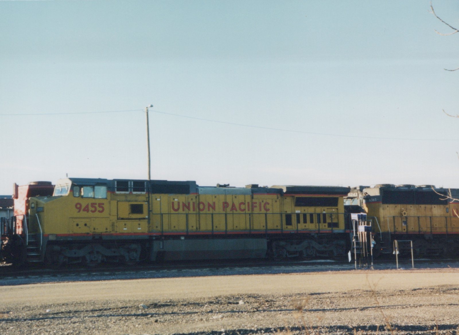 A side view of a yellow Union Pacific diesel locomotive numbered 9455, with two other locomotives behind it, on a clear winter day in a rail yard.