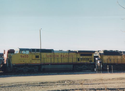 A side view of a yellow Union Pacific diesel locomotive numbered 9455, with two other locomotives behind it, on a clear winter day in a rail yard.
