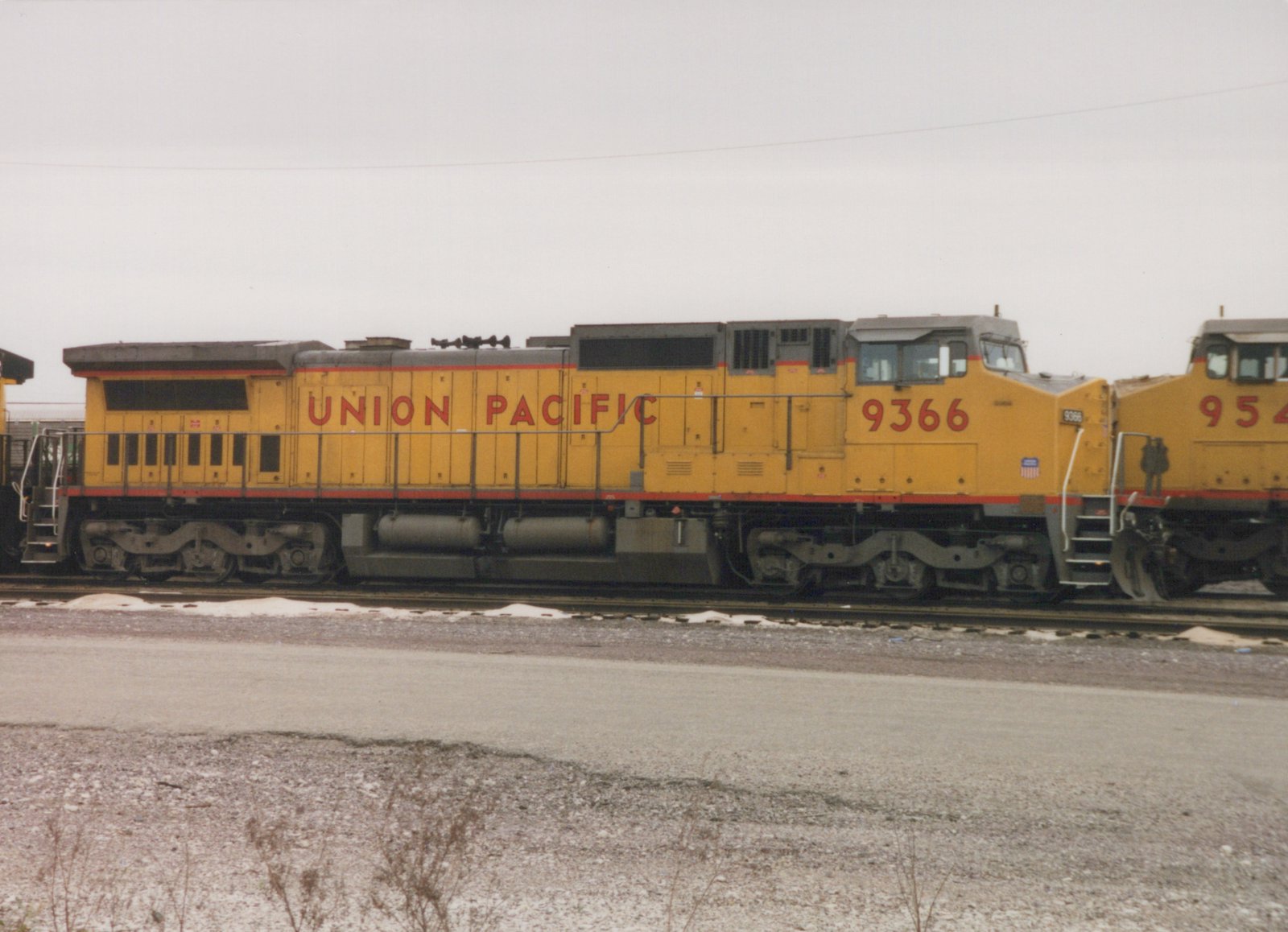 Union Pacific locomotive number 9366, a yellow SD40-2 diesel, sits on tracks in a snowy yard with another locomotive beside it.