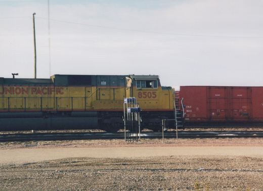 A yellow and red Union Pacific locomotive numbered 8505 stands on tracks beside a red boxcar numbered 8643, in what appears to be a rail yard.