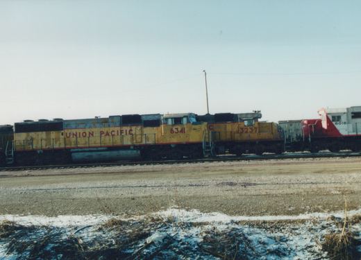 Three diesel locomotives in a snowy yard; the lead is Union Pacific 6341 in yellow and red, followed by UP 3237 and a Wisconsin Central unit in red and white.