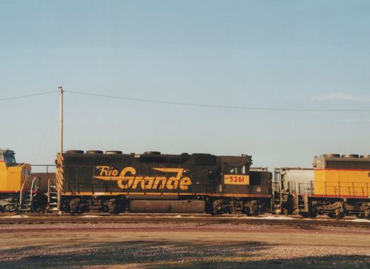 Two Union Pacific diesel locomotives are parked on parallel tracks in a sunny railyard; the front locomotive is black with yellow 'Rio Grande' lettering.