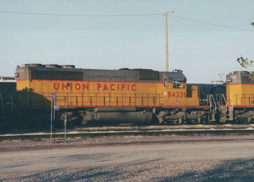 A yellow and gray Union Pacific diesel locomotive numbered B4226 seen from the side on a yard track, with a black tank car and another yellow locomotive numbered 2987 behind it.