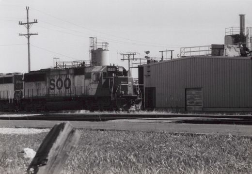 A black and white photograph of two SOO Line diesel locomotives, 6008 and 6015, standing side by side in a rail yard on a cloudy day.