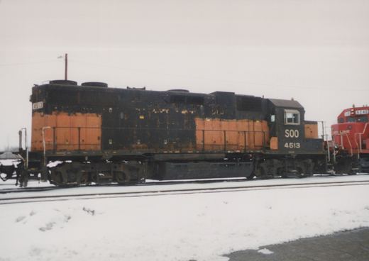 Two SOO Line diesel locomotives, 4513 and 6240, are seen side-by-side on snowy tracks in a rail yard under an overcast sky.