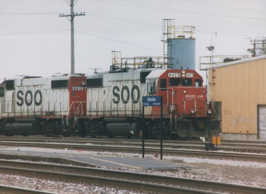 Two SOO Line diesel locomotives, numbers 4429 and 4419, are stopped at the Mannheim station platform on a cloudy day with snow on the ground.