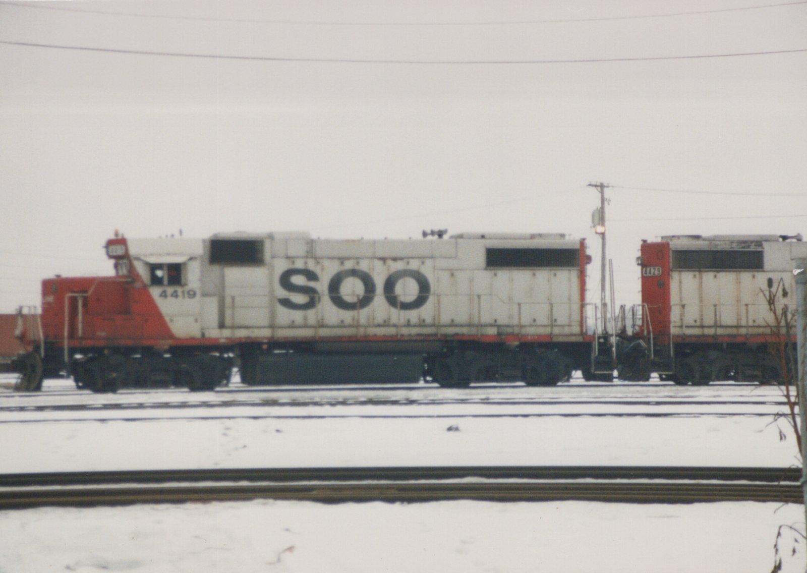Side view of two white and red Soo Line diesel locomotives, numbered 4419 and 4429, parked on parallel tracks in a snowy railyard.