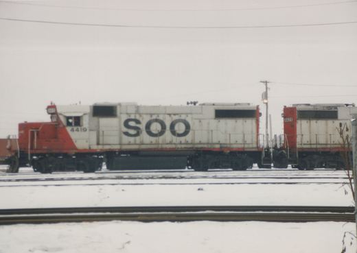 Side view of two white and red Soo Line diesel locomotives, numbered 4419 and 4429, parked on parallel tracks in a snowy railyard.