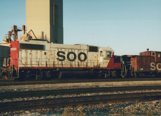 A Soo Line EMD SD40-2 diesel locomotive, numbered 4400, stands coupled to a red caboose, numbered 131, on a set of railroad tracks under a clear blue sky.
