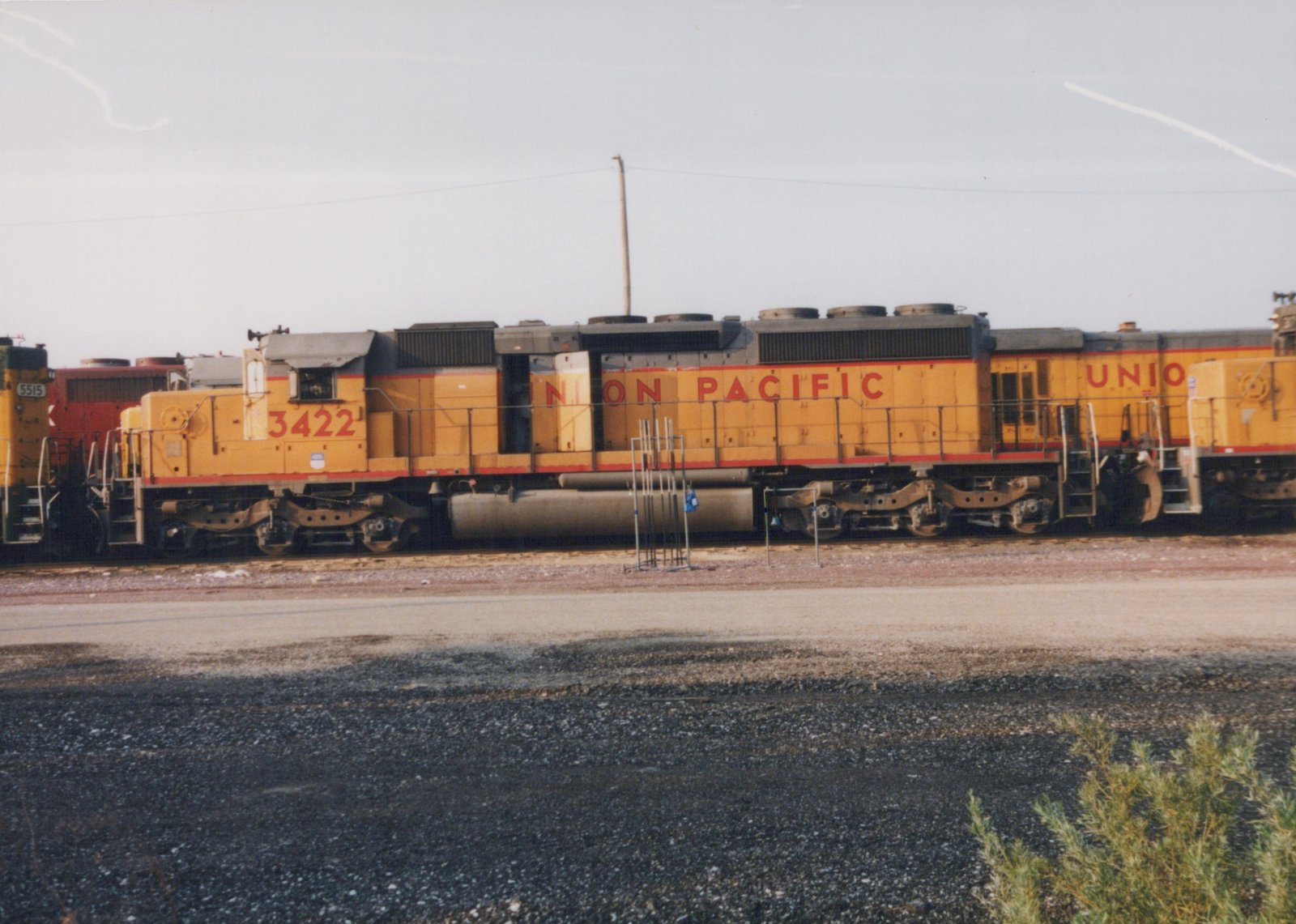 Side view of a yellow Union Pacific locomotive numbered 3422 standing in a rail yard, with another locomotive visible behind it.