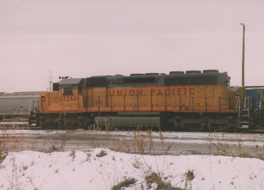 A yellow and gray Union Pacific diesel locomotive numbered B3266 is parked on railroad tracks with snow covering the ground in the foreground.